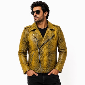 Puede incluir: Una chaqueta de motorista color amarillo mostaza con un patrón texturizado de piel de serpiente, cierre de cremallera asimétrico plateado, solapas, charreteras en los hombros, bolsillos laterales con cremallera y cinturón con hebilla.