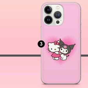 May include: Pink phone case featuring a cartoon image of Hello Kitty and Kuromi hugging, set against a pink heart-shaped background. The case has a clear border and a camera cutout.