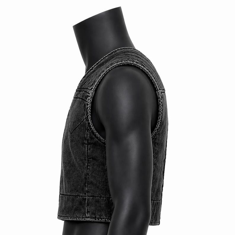 May include: A dark gray denim vest with a classic design. The vest features a V-neck, a button-up front, and a cropped length. The vest is displayed on a black mannequin.