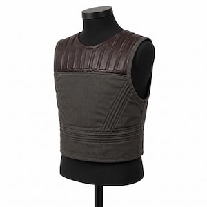 May include: A dark gray vest with a brown leather upper section. The vest has a quilted design on the shoulders and horizontal stitching across the lower section. It is displayed on a black mannequin.