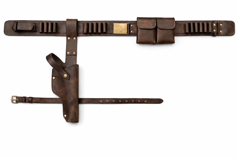 May include: A brown leather gun belt with a holster, cartridge holders, and pouches. The belt features a buckle, brass accents, and a strap for the leg. The leather has a distressed finish.