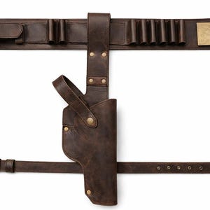 May include: A brown leather gun belt with a holster, cartridge holders, and a buckle. The belt features a brass buckle and rivets, and is designed to be worn around the waist. The holster is attached to the belt.