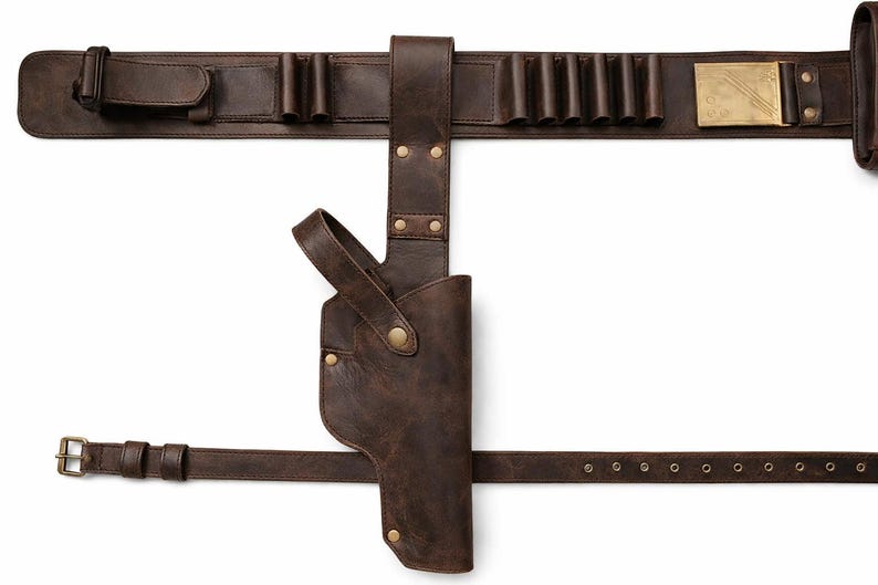 May include: A brown leather gun belt with a holster, cartridge holders, and a buckle. The belt features a brass buckle and rivets, and is designed to be worn around the waist. The holster is attached to the belt.