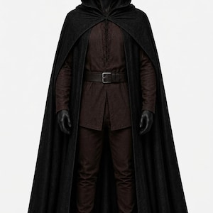 May include: A full-length black hooded cloak worn over a dark brown long-sleeved tunic with a lace-up front, a matching dark brown belt with a rectangular buckle, dark brown trousers, and black boots on a faceless mannequin figure.