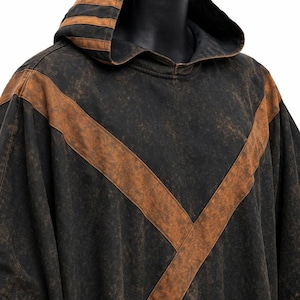 May include: Black hooded poncho with brown accents. The poncho features a large V-shaped brown stripe across the front and brown stripes on the hood. The fabric has a distressed, vintage look.