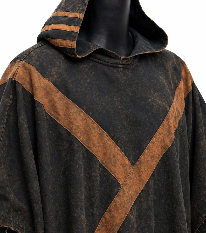 May include: Black hooded poncho with brown accents. The poncho features a large V-shaped brown stripe across the front and brown stripes on the hood. The fabric has a distressed, vintage look.