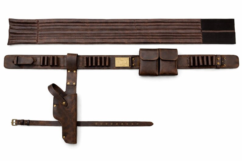 May include: A brown leather gun belt with a holster, cartridge holders, and two pouches. The belt includes a separate band for the back and a smaller belt with a buckle. The leather has a distressed appearance.