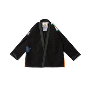 Puede incluir: Una chaqueta de kimono para artes marciales de color negro con mangas largas, cuello reforzado con costuras verdes y paneles laterales naranjas. El forro interior muestra un patrón geométrico colorido y el exterior incluye detalles bordados en azul.