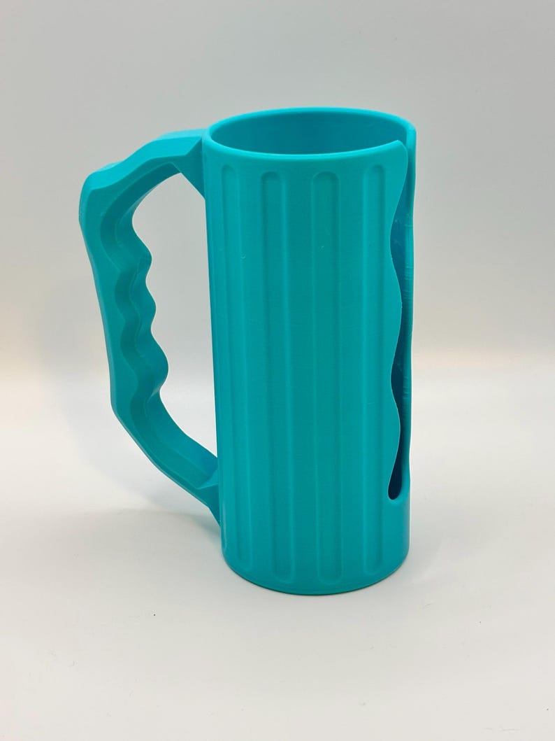 May include: A teal-colored, cylindrical mug with a large handle. The mug has vertical ridges along its body and a curved cutout on one side. The handle is designed for a comfortable grip. The mug is made of a solid, opaque material.
