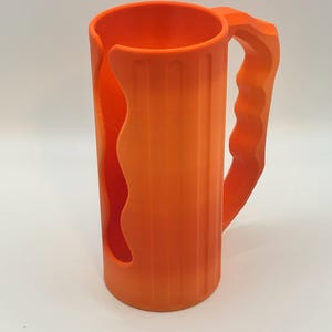 May include: Bright orange mug with a handle and a unique cutout design. The mug has vertical ridges and a curved handle for easy gripping. The mug is made of a solid, opaque material and is suitable for beverages.
