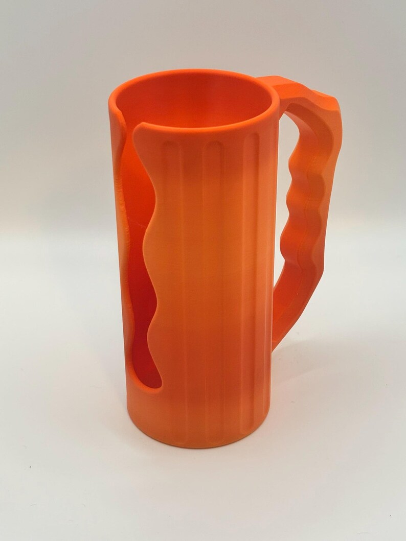 May include: Bright orange mug with a handle and a unique cutout design. The mug has vertical ridges and a curved handle for easy gripping. The mug is made of a solid, opaque material and is suitable for beverages.