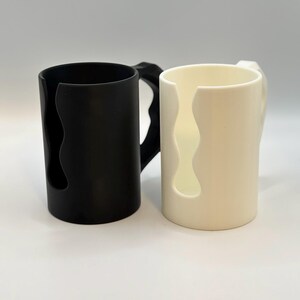 May include: A set of three ceramic mugs with a speckled, matte finish. The mugs are in shades of cream, light gray, and dark gray. Each mug has a simple, minimalist design, perfect for coffee or tea.