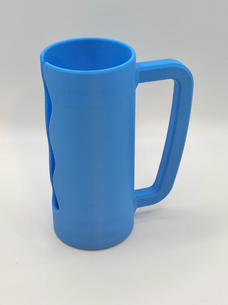 May include: A light blue, 3D-printed mug with a large handle and a unique wave-like cutout on the side. The mug is cylindrical with a flat bottom and a wide opening. The handle is rectangular and attached to the side of the mug.
