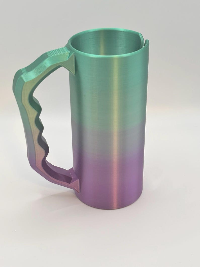 May include: A tall, cylindrical mug with a large handle. The mug features a gradient color scheme, transitioning from green at the top to purple at the bottom. The handle is a matching gradient of green and purple.