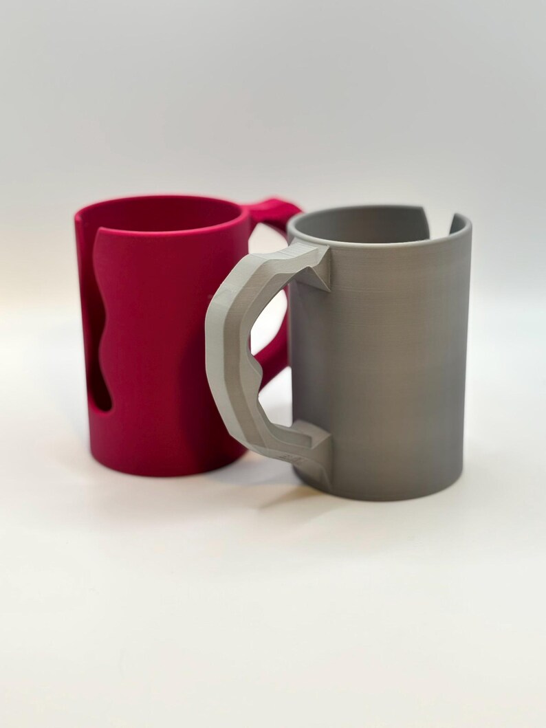 May include: A set of three ceramic mugs with a speckled, cream-colored glaze. Each mug features a different hand-painted design: a blue and green leaf, a yellow flower, and a red berry. The mugs have a simple, rounded shape.