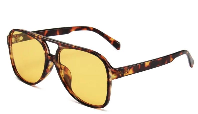 May include: Aviator-style sunglasses with a tortoiseshell frame and yellow-tinted lenses. The sunglasses have a double bridge and thick temples. The lenses are a bright yellow color, and the frame has a brown and black pattern.