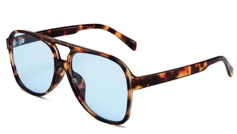 May include: Aviator-style sunglasses with a tortoiseshell frame and light blue lenses. The sunglasses have a double bridge and thick temples. The lenses are a light blue color, and the frame has a brown and black pattern.