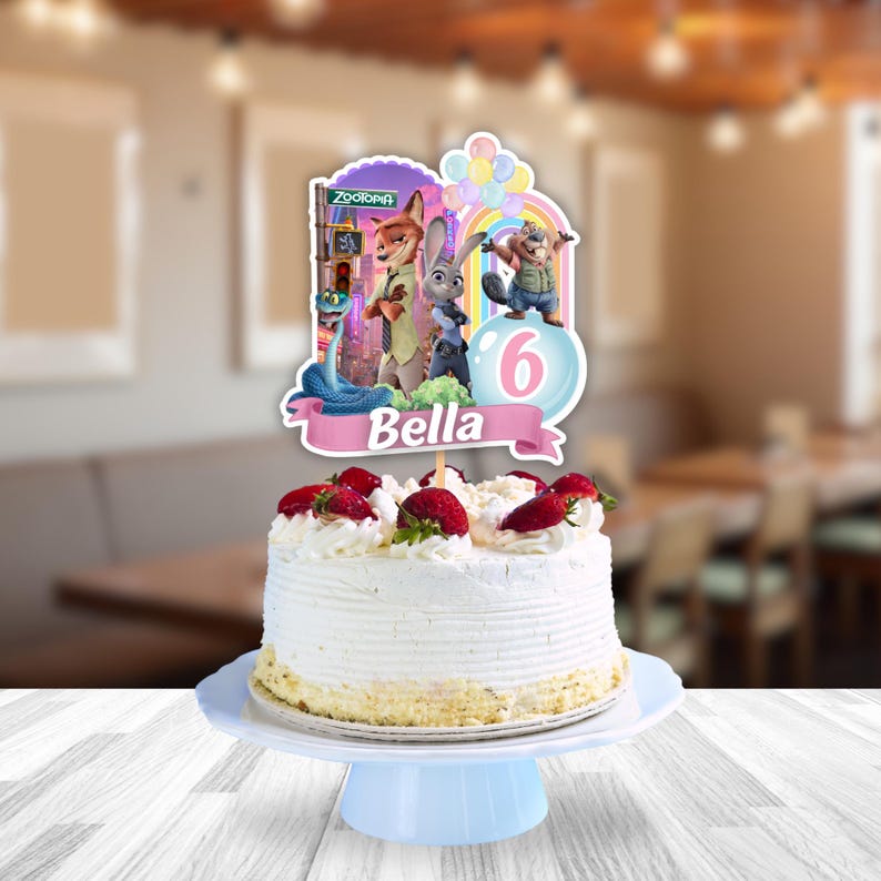 May include: A round white frosted cake topped with fresh strawberries and whipped cream, featuring a Zootopia-themed cake topper with characters, a rainbow, balloons, the number 6, and a pink banner with the name Bella printed in white.