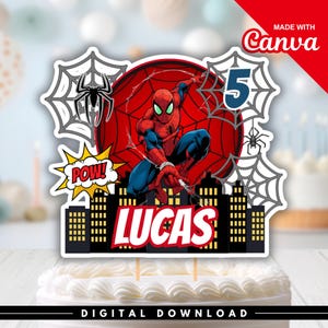 Puede incluir: Un adorno para pastel con el personaje de Spider-Man en rojo y azul, el número 5 grande y el nombre LUCAS en letras blancas. El diseño incluye telarañas negras, una burbuja de texto amarilla con POW y una silueta de ciudad negra.
