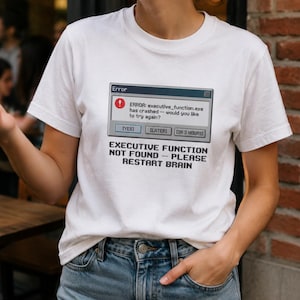 May include: A white short-sleeved t-shirt featuring a graphic of a computer error message that reads: ERROR: executive_function.exe has crashed - would you like to try again? Below the box, the text reads: EXECUTIVE FUNCTION NOT FOUND - PLEASE RESTART BRAIN.