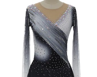 May include: A figure skating dress with a black and white gradient design. The long-sleeved dress features a sheer neckline and is embellished with sparkling rhinestones. The skirt is black, and the sleeves fade to a sheer white.