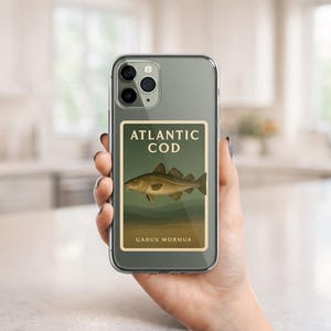 May include: A clear phone case displaying a sticker with the words "ATLANTIC COD" above an illustration of a fish. The fish is light brown with dark brown markings. The text "GADUS MORHUA" is below the fish.