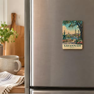 a kitchen scene with a refrigerator magnet depicting a scenic view of Savannah, Georgia. The refrigerator is positioned on the right side of the image, and there is a wooden cutting board and a mug on the left side.