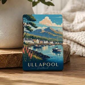 May include: A rectangular magnet featuring a colorful illustration of the coastal village of Ullapool, Scotland. The scene depicts a harbor with boats, white buildings, mountains, and pink flowers, with the text ULLAPOOL Scotland printed at the bottom.