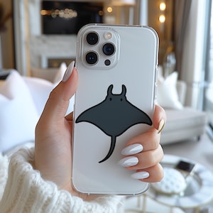 May include: Clear phone case featuring a dark gray manta ray design. The case is transparent, allowing the phone's color to show through. The manta ray illustration is centered on the back of the case. The phone case has a protective bumper around the edges.