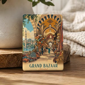 May include: A rectangular magnet featuring a colorful illustration of the Grand Bazaar in Istanbul. The artwork depicts a bustling market corridor with arched ceilings, hanging lanterns, and people walking, with the text GRAND BAZAAR Istanbul below.