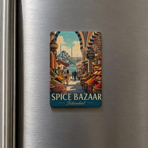 May include: A rectangular refrigerator magnet featuring a colorful illustration of the Spice Bazaar in Istanbul. The image displays stalls with mounds of spices, arched architecture, and the text SPICE BAZAAR Istanbul at the bottom.