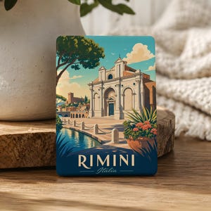 May include: A rectangular souvenir magnet featuring a colorful illustration of a historic building in Rimini, Italy. The scene includes a blue canal, a stone plaza, a large tree, and a potted plant with pink flowers. The text RIMINI Italia is at the bottom.