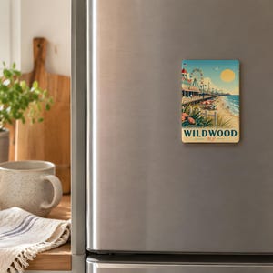 a refrigerator with a vintage-style magnet depicting a beach scene, including a pier and a building, as well as a wooden cutting board and a mug on the kitchen counter.