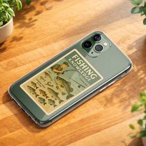 May include: A clear phone case with a green tint, featuring a "Fishing Knowledge" graphic. The graphic includes illustrations of fish, bait, and a fisherman. The phone rests on a wooden surface, surrounded by potted plants.