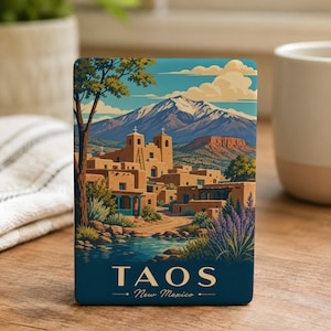 May include: A rectangular Taos, New Mexico art print featuring a landscape with adobe buildings, a river, and mountains under a blue sky. The print has the text "TAOS" and "New Mexico".