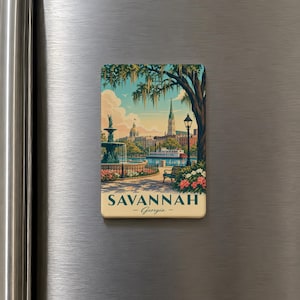 A vintage-style magnet depicting a scenic view of Savannah, Georgia, with a fountain, trees, and buildings in the background.
