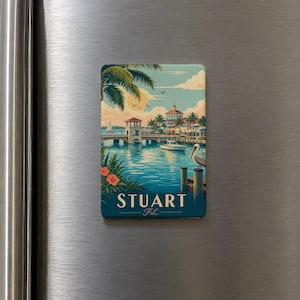 May include: A rectangular magnet featuring a scenic illustration of Stuart, Florida. The artwork depicts a waterfront scene with a bridge, boats, palm trees, and a pelican. The word "STUART" is prominently displayed, with "FL" below it.