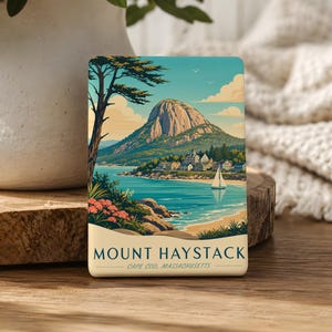 May include: A rectangular Mount Haystack Cape Cod, Massachusetts art print. The image features a coastal landscape with a mountain, ocean, beach, and a sailboat. The color palette includes blues, greens, and beige, with a vintage travel poster aesthetic.