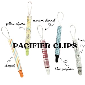 Puede incluir: Una colección de cinco clips para chupetes con varios diseños. Los clips incluyen diseños de rayas, flores, franela granate, cuadros azules y leones. Cada clip tiene un lazo en la parte superior y una pinza de plástico en la parte inferior.