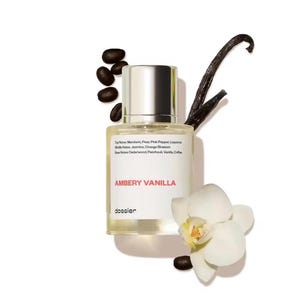 May include: A perfume bottle with a silver cap and a white label that reads "AMBERY VANILLA." The bottle is surrounded by coffee beans, a vanilla bean, and a white orchid. The label lists the top, middle, and base notes of the fragrance.
