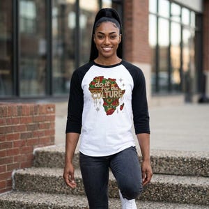 May include: A white and black raglan shirt with the text "do it for the CULTURE" and a map of Africa in red, green, and gold. The shirt has three-quarter length black sleeves.