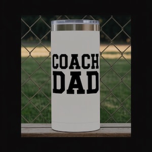 Könnte beinhalten: Ein weißer Becher mit einem transparenten Deckel. Die Worte "COACH DAD" sind in fetten, schwarzen Buchstaben auf der Vorderseite aufgedruckt. Der Becher ist zylindrisch und scheint aus Edelstahl zu sein.