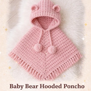 Könnte beinhalten: Ein rosa gehäkeltes Baby-Poncho mit Kapuze in Bärenform und zwei Bommeln. Der Poncho hat einen Fransenbesatz und ist für Größen von 0-24 Monaten geeignet. Der Text "PDF Crochet Pattern" ist ebenfalls enthalten.