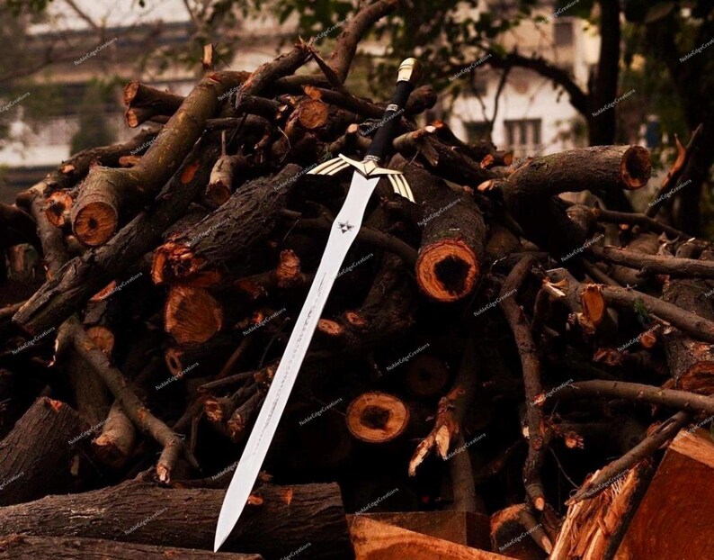 May include: A silver and black sword with a decorative gold hilt and a long, pointed blade. The sword is displayed against a backdrop of stacked, dark brown logs, creating a rustic and dramatic contrast.