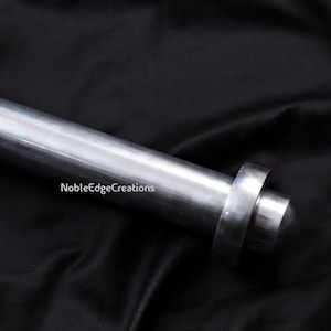 May include: A close-up of a silver metal rod with a rounded end and a circular ring. The rod is set against a black background. The text "NobleEdgeCreations" is visible on the image.
