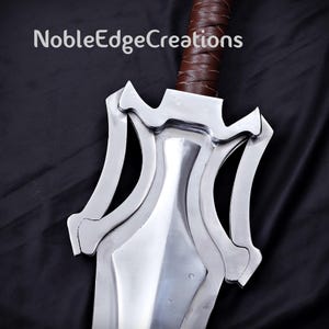 May include: Close-up of a silver sword with a brown leather-wrapped handle. The sword has a unique design with curved edges and a pointed tip. The text "NobleEdgeCreations" is visible at the top.