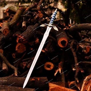 May include: A silver sword with a blue and white handle rests on a pile of brown logs. The sword has a detailed hilt and a long, sharp blade. The logs are cut and stacked, creating a rustic backdrop.