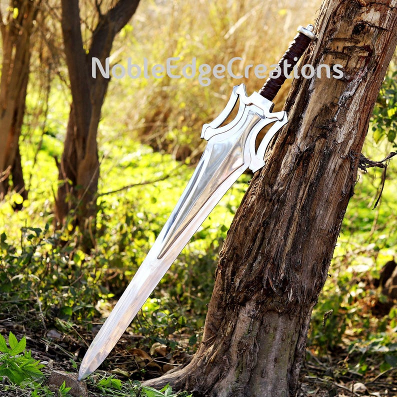 May include: A large, silver sword with a decorative hilt and a brown leather-wrapped handle. The blade is long and pointed, with a polished finish. The sword is leaning against a tree trunk. The text "Noble Edge Creations" is visible.