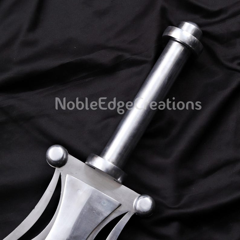 May include: Close-up of a silver sword with a cylindrical handle and a decorative crossguard. The sword has a polished finish and the text "NobleEdge Creations" is visible.