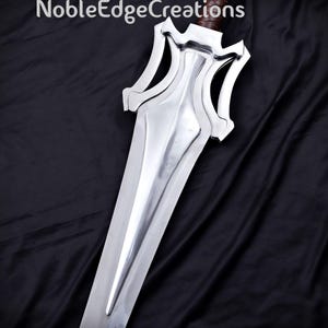 May include: A silver sword with a unique hilt design and a brown handle. The blade is long and polished, reflecting the light. The sword is set against a dark background, with the text "NobleEdgeCreations" at the top.
